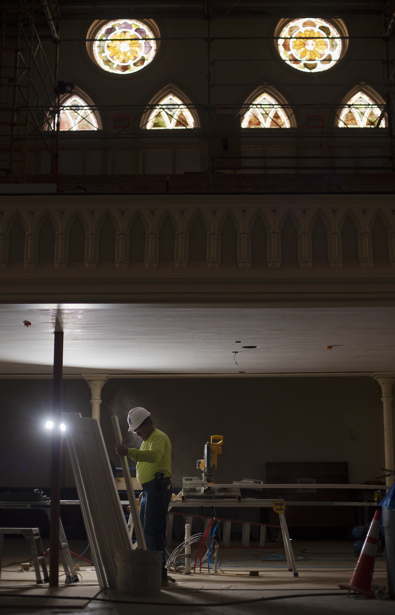 A construction worker is lit by worklight as sun streams through stained glass in the balcony of the great hall during construction at UPH Monday, Novermber 11, 2019. Photo credit: Kate Penn - Proctors